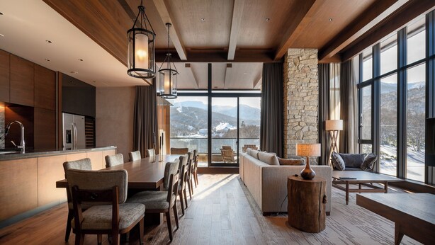 A spacious living area with a large dining table, comfortable seating, and a stone accent wall. - Yu Kiroro (Akaigawa)