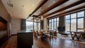 A modern kitchen with a central island, wooden flooring, and large windows offering mountain views. - Yu Kiroro (Akaigawa)