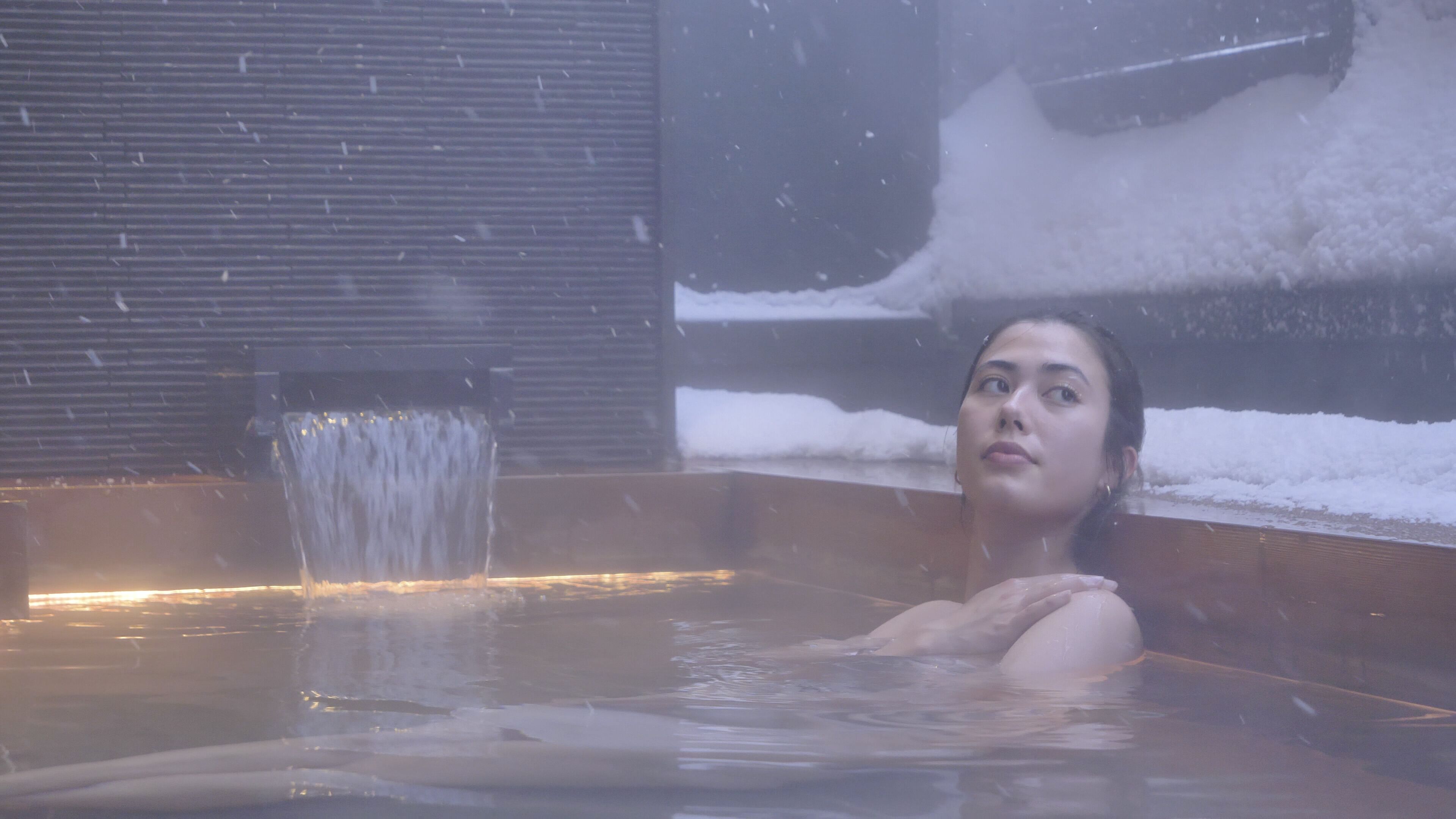 Una persona en un jacuzzi, con nieve afuera.