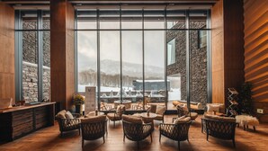 A spacious indoor area with large windows, wooden flooring, and wicker furniture. - Yu Kiroro (Akaigawa)