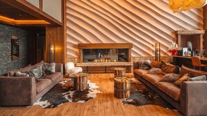 Una sala de estar moderna con chimenea, sofás de cuero, suelo de madera y un diseño de techo ondulado único.