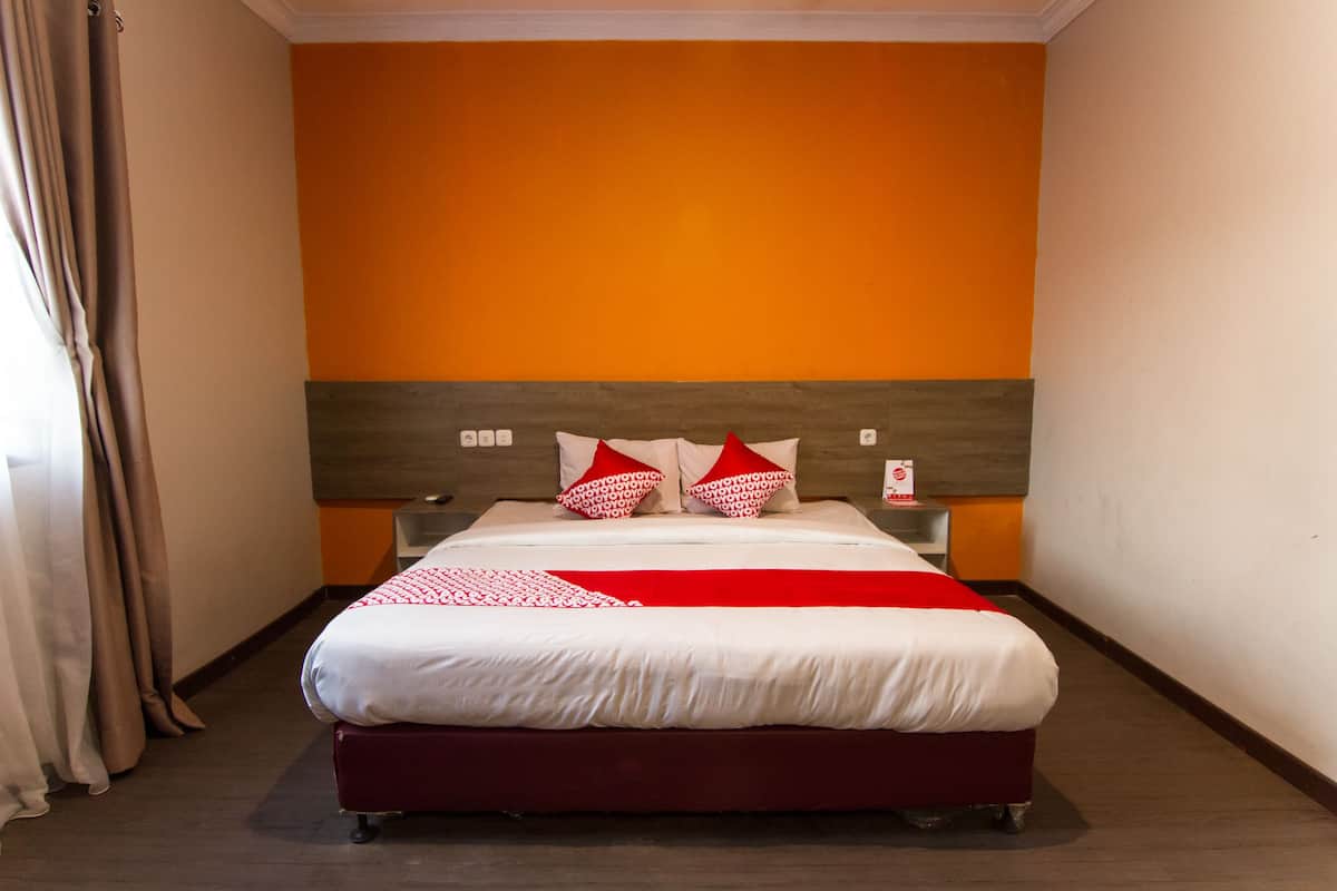 A hotel room with a bed, a headboard, and a wall painted in two colors.