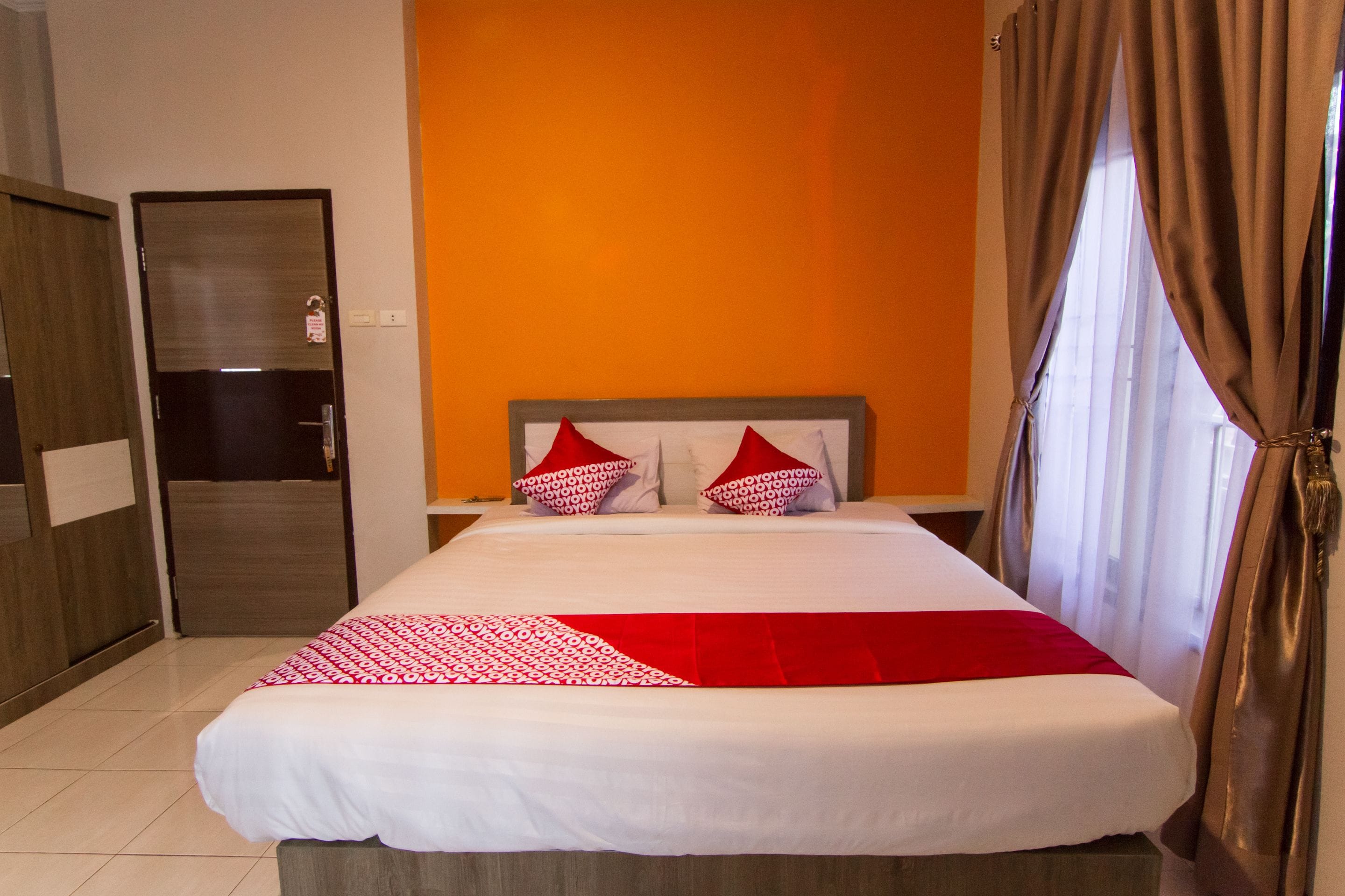 Une chambre d’hôtel avec un lit, une armoire et un mur orange.