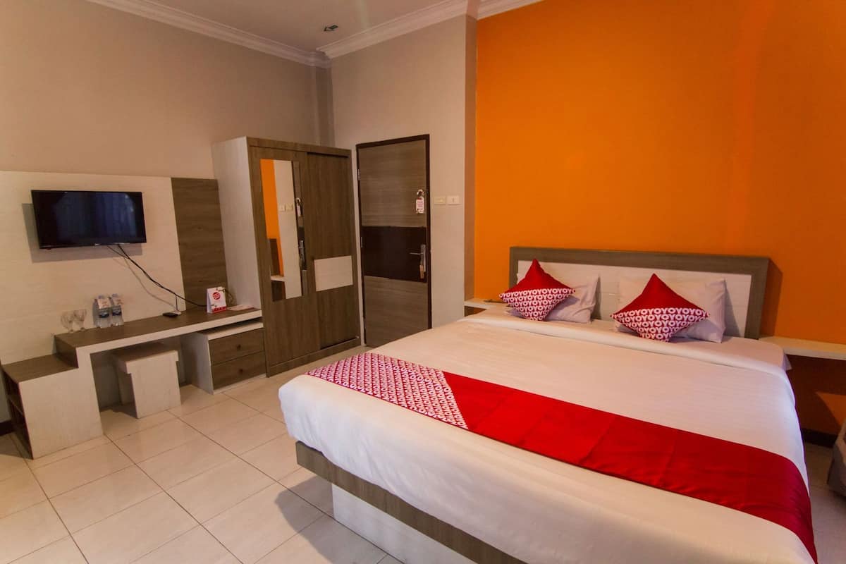 A hotel room with a bed, a TV, a desk, and a wardrobe.