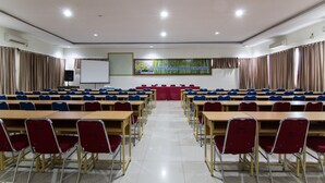 A conference room with rows of desks and chairs, a whiteboard, and a projector screen.
