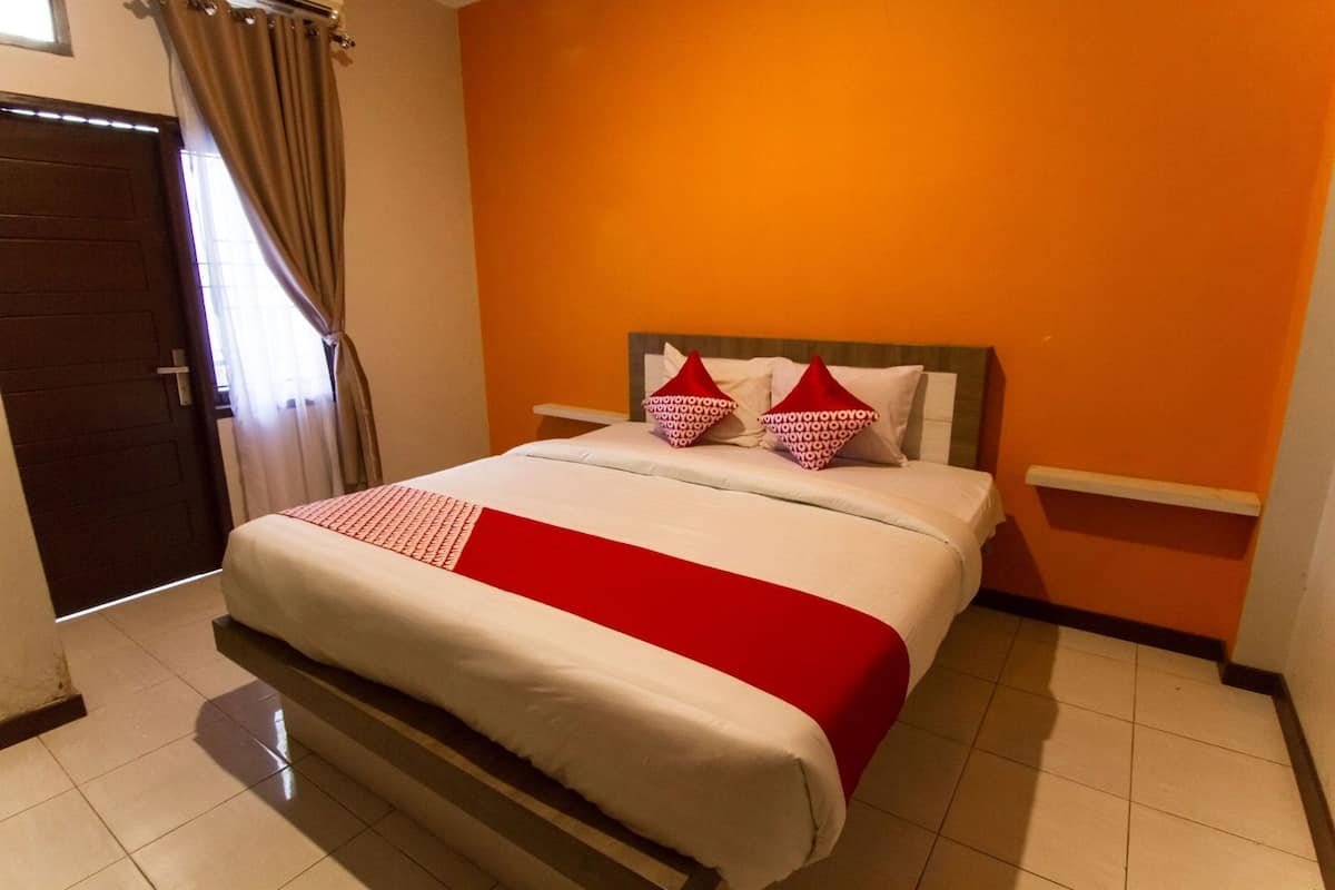 A hotel room with a bed, a nightstand, a door, and a window with curtains.