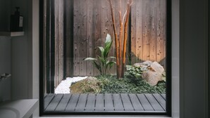 Een moderne badkamer met een groot raam, een houten vloer en een ingebouwd plankje.