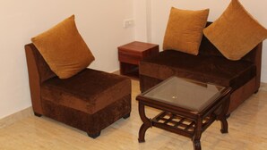 A small, furnished living area with two brown sofas, a glass coffee table, and a wooden side table. - Red Crown Hotel (New Delhi)