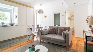 A modern living room with a grey sofa, a coffee table, and a dining area with a small table and chairs.