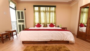 A bedroom with a large bed, two nightstands, a wooden wardrobe, and a balcony door. - Hotel Tenancy (Gangtok)