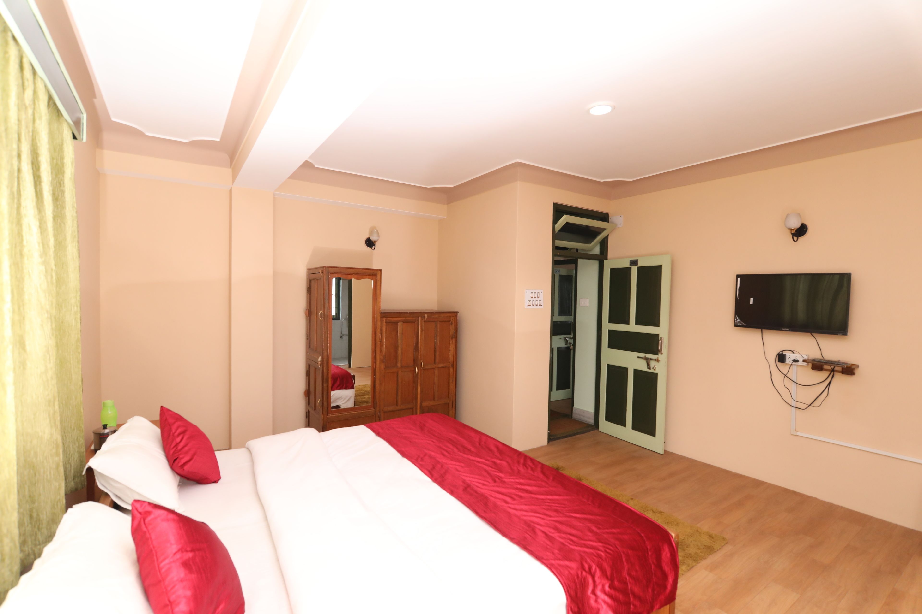 A bedroom with a bed, a wardrobe, a television, and a bathroom door.