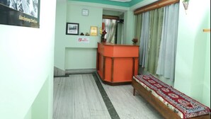 A reception area with a desk, a bench, and a wall-mounted sign. - Hotel Tenancy (Gangtok)