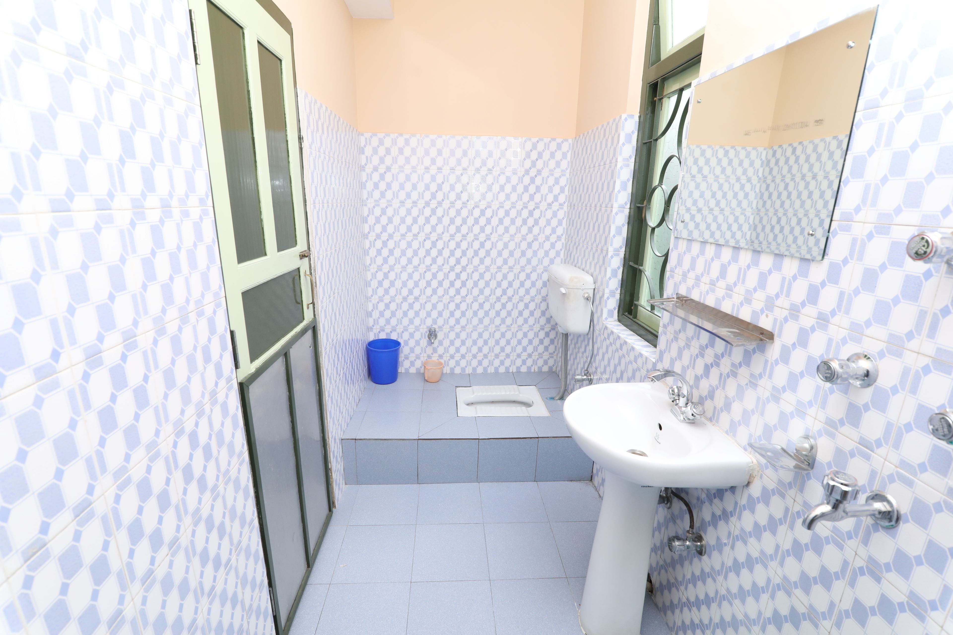 A bathroom with checkered blue and white tiles, a white sink, a toilet, and a blue bucket.