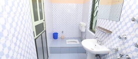 A bathroom with checkered blue and white tiles, a white sink, a toilet, and a blue bucket.