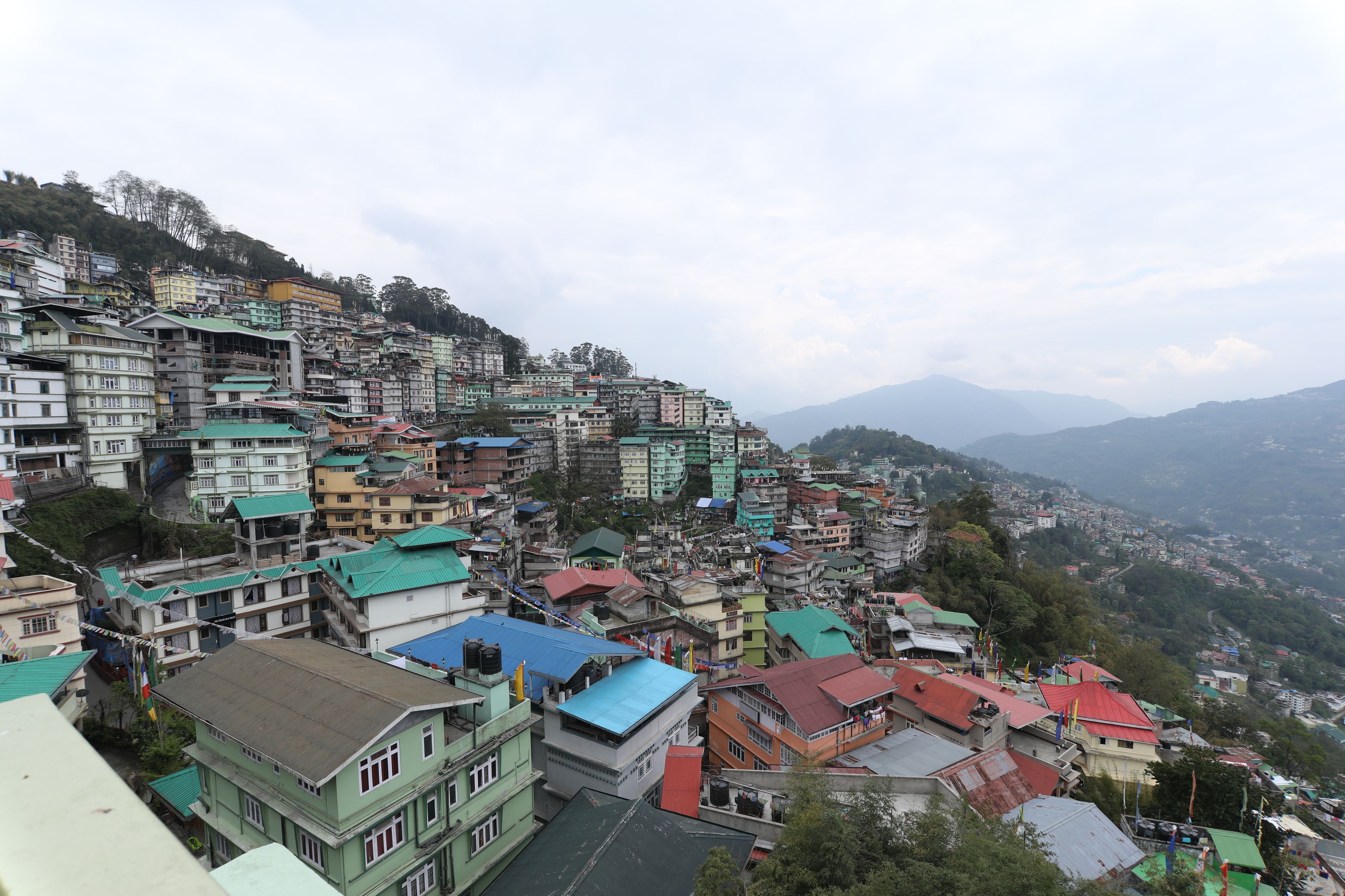 Una zona residencial con construcciones apretadas en una ladera, con edificios de varios pisos, algunos con balcones y colores de techo variados.