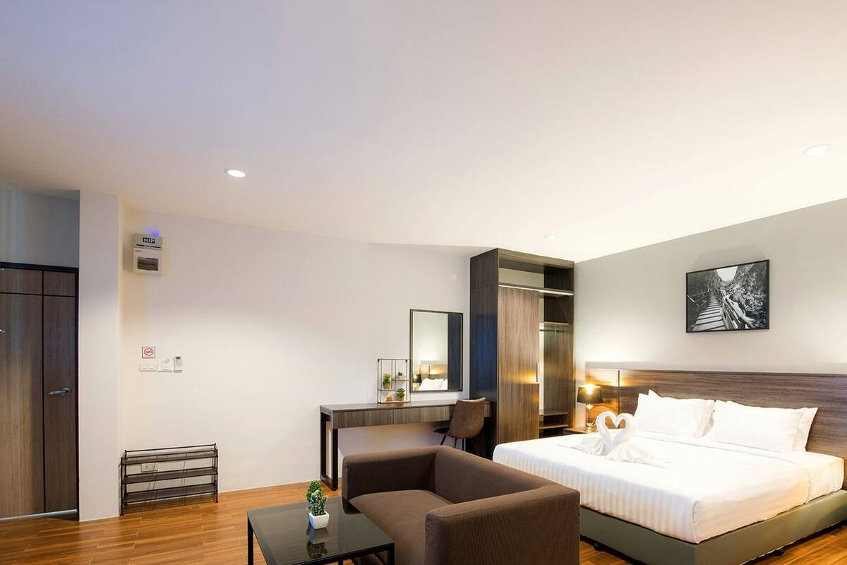 Moderni hotellihuone, jossa on sänky, yöpöydät, työpöytä, tuoli ja vaatekaappi.