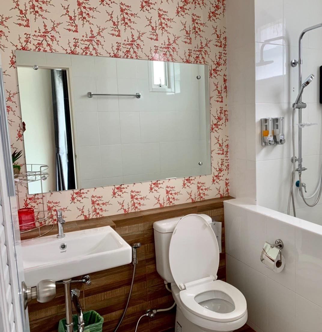 A bathroom with a white toilet, a sink, a mirror, and a shower area.