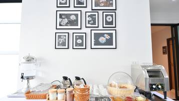 A breakfast buffet setup with a coffee machine, tea station, and various food items.