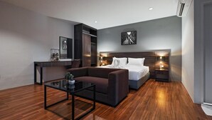 Una habitación de hotel moderna con una cama grande, un sofá, una mesita y un escritorio.