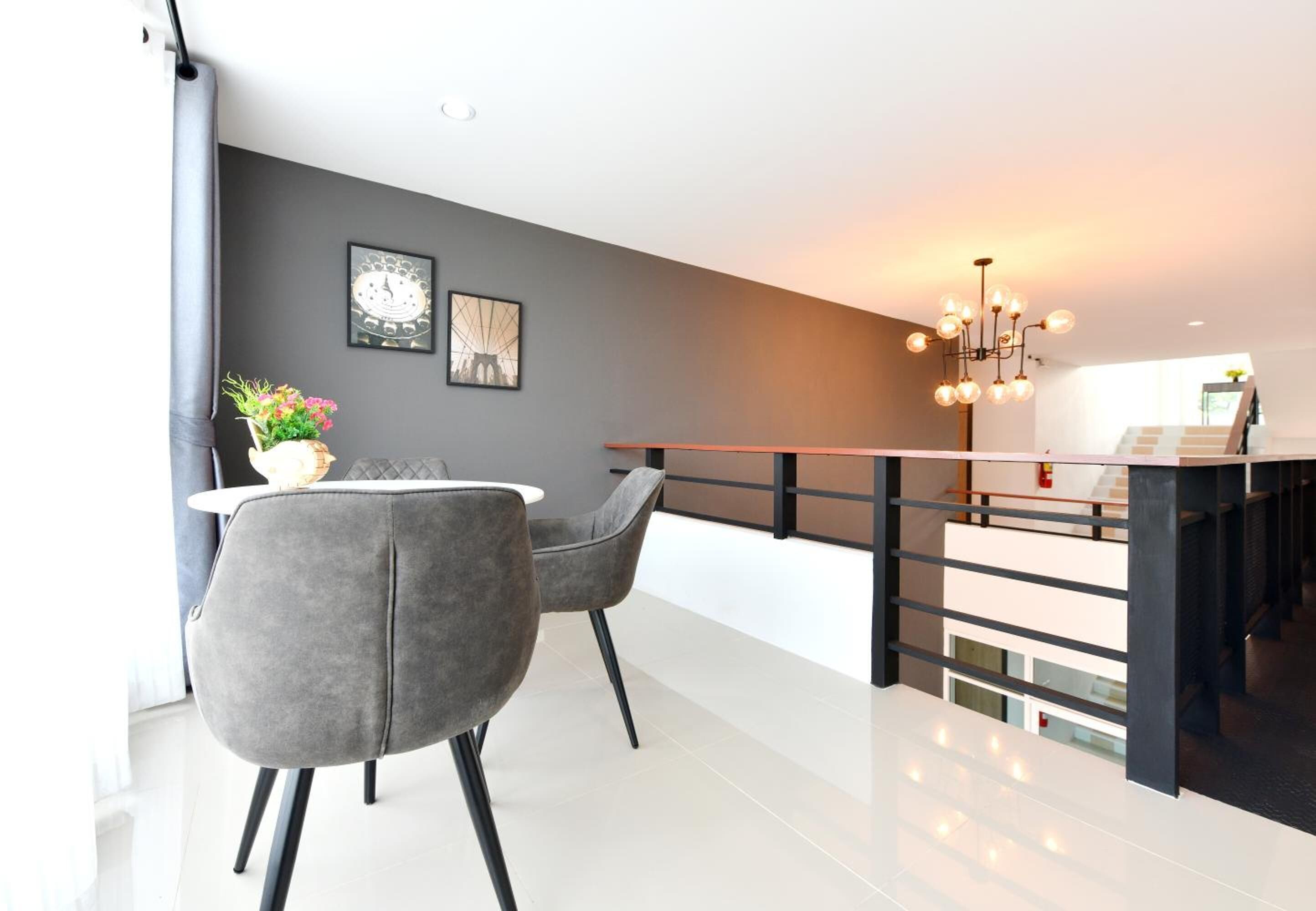 Et moderne spiseområde med en grå polstret stol, et hvidt bord og en dekorativ vase.