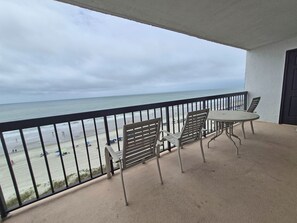Un balcón con mesa y sillas con vista a la playa.