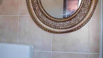 Un baño con un espejo redondo, un lavamanos y un inodoro.