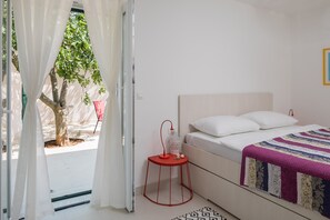 A bedroom with a bed, a bedside table, a window with curtains, and a view of a tree outside. - Book Villa Basic and get relaxed with wine and beautiful sunset from top floor (Dvornica)