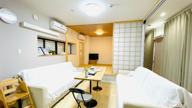 Habitación de hotel con dos camas, una mesita, una silla, un televisor y un panel corredero shoji.