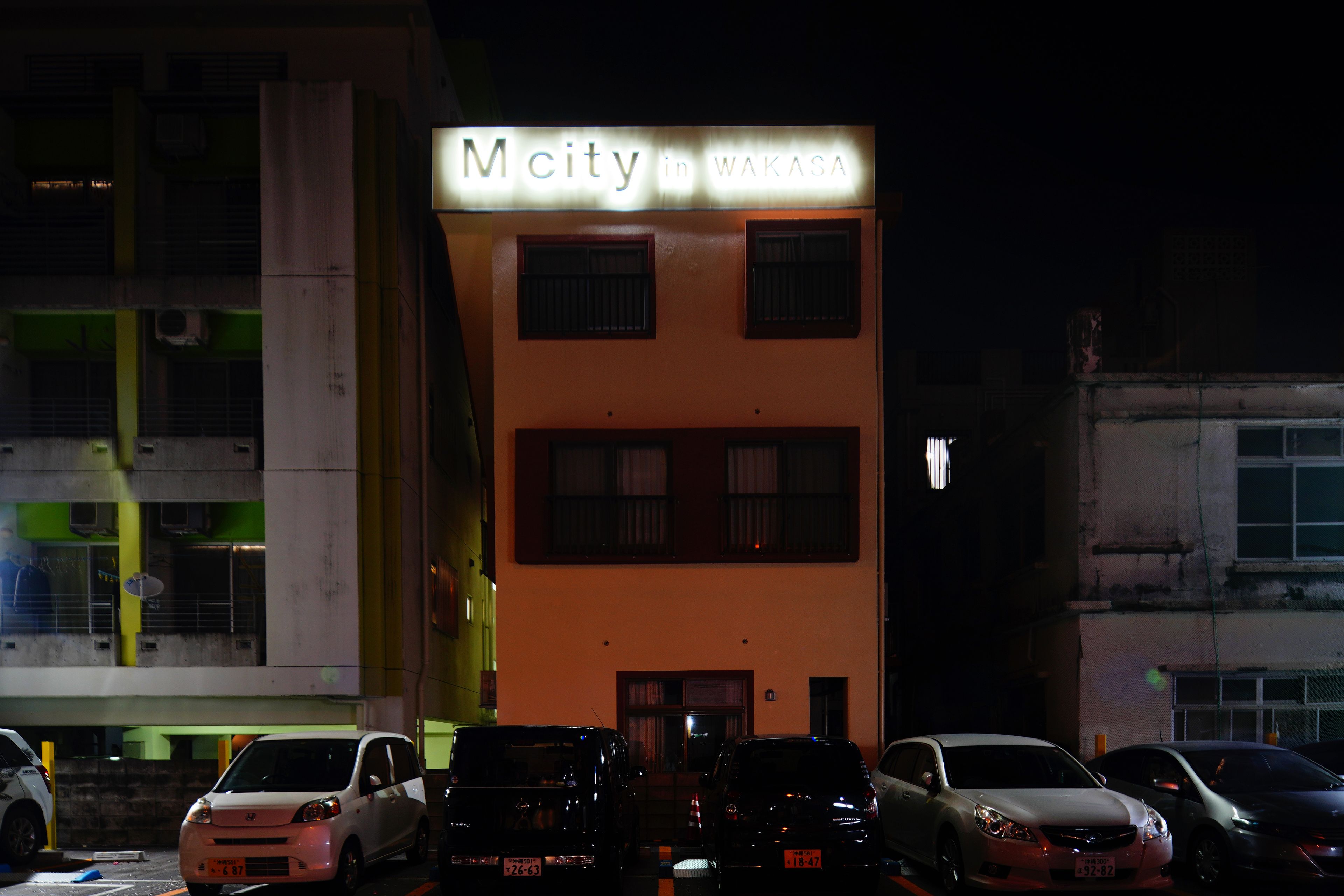 A building with a sign reading "Mcity in WAKASA" at night.