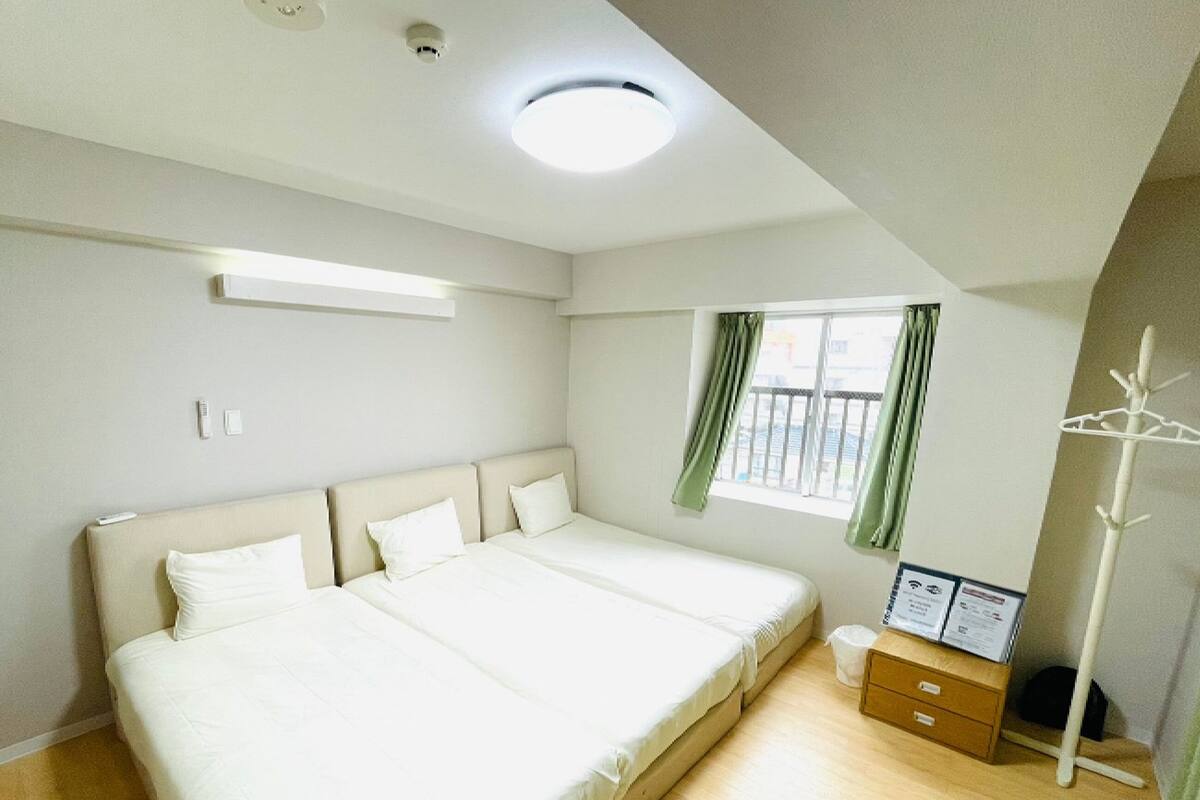 Quarto com uma cama grande, janela com cortinas, mesa de cabeceira e luminária no teto.