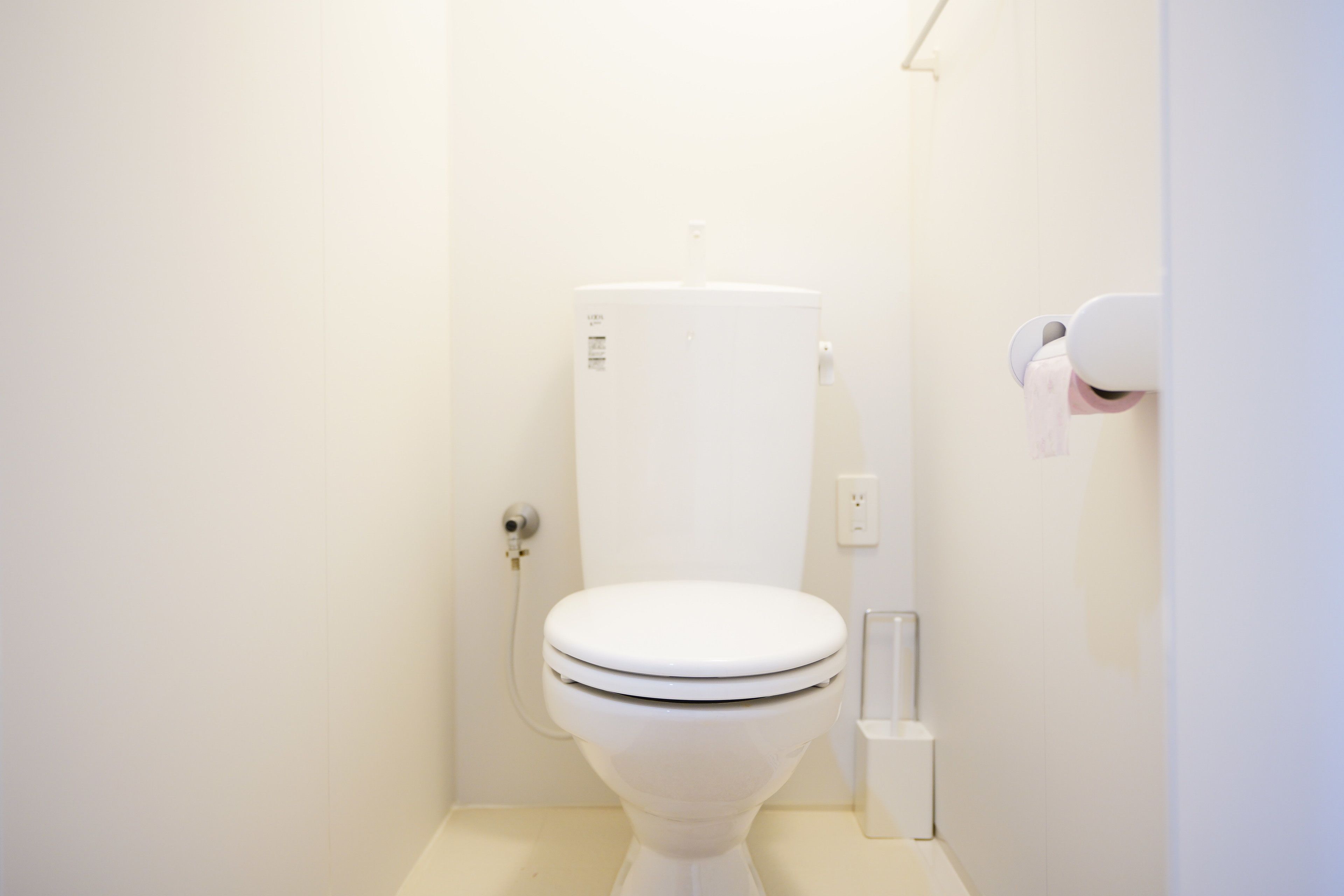 A white toilet in a bathroom with a white wall and floor.