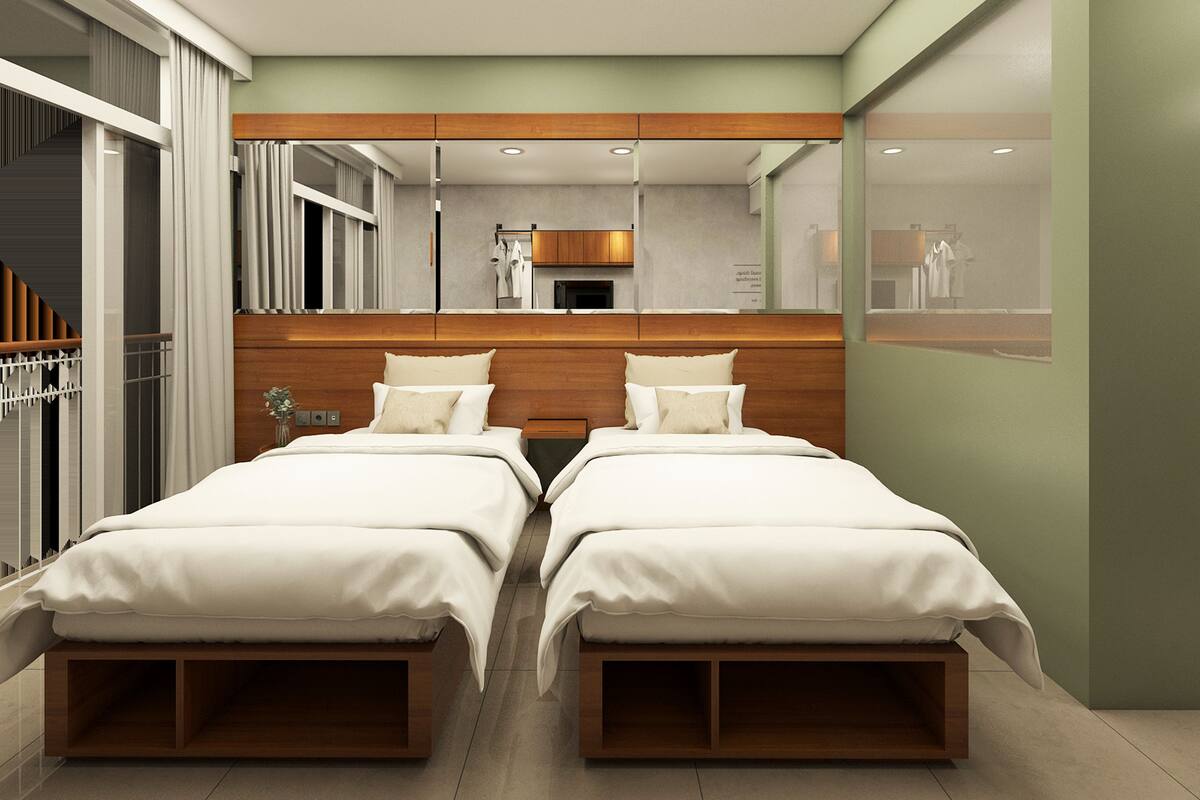 Quarto de hotel moderno com duas camas, cabeceira de madeira, um espelho grande e vista para o exterior.