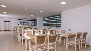 A dining area with multiple tables and chairs, a bar in the background, and large windows with blinds. - Hilal Hotel Tashkent (Tashkent)
