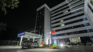 A modern hotel building at night with a well-lit entrance and a car parked in front. - Hilal Hotel Tashkent (Tashkent)