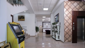 A clean, modern lobby with a reception desk, a vending machine, and a staircase leading to an upper level. - Hilal Hotel Tashkent (Tashkent)