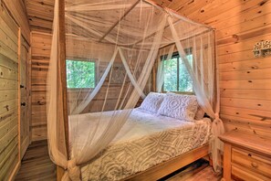 Une chambre dans une cabane en bois, avec un lit à baldaquin, une table de chevet et une fenêtre.
