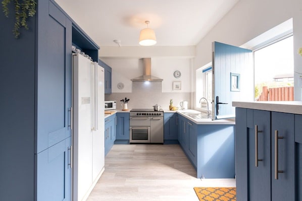 Bright kitchen with back door opening to the raised decked dining area, pet-friendly beachside cottage sleeping six in Rhosneigr, Anglesey