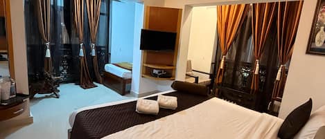 A hotel room with a large bed, a ceiling fan, a flat-screen TV, and a mirror.