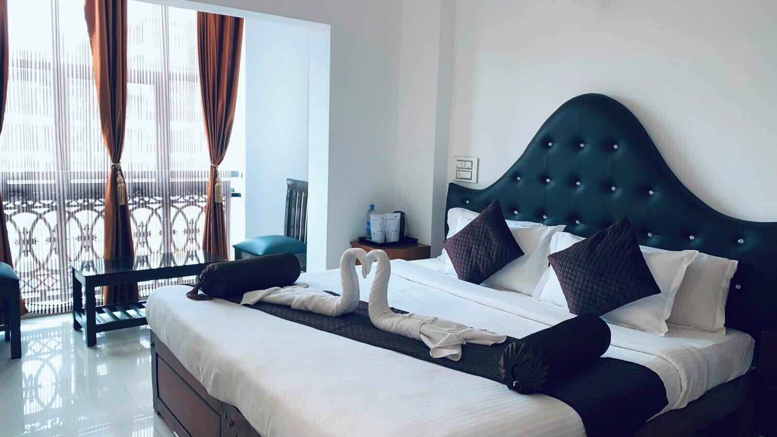 Habitación de hotel con una cama grande, una mesita de noche, una silla y vistas al exterior.