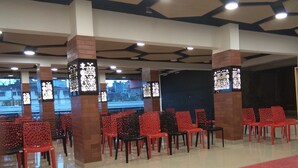 A spacious indoor area with rows of red and black chairs arranged for seating. - Hotel Al Wesal International (Madikeri)