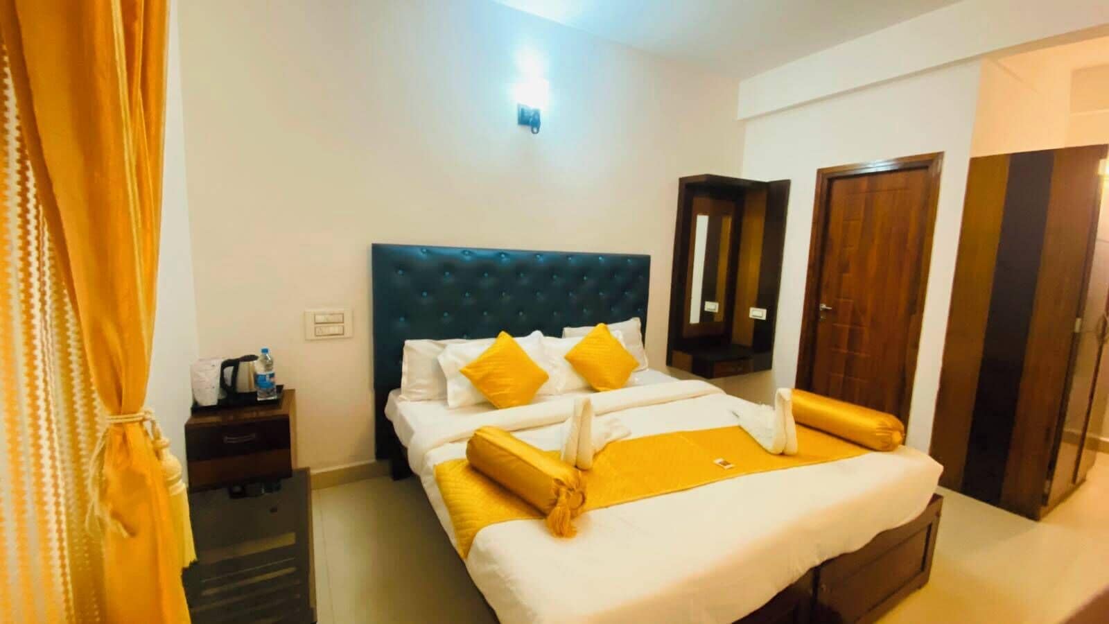A hotel room with a bed, a nightstand, a mirror, and a wardrobe.