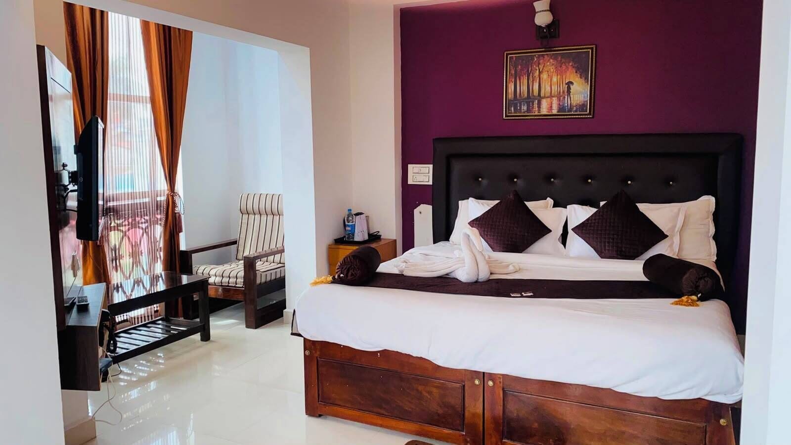 Habitació d'hotel amb un llit, una cadira, una televisió i un quadre a la paret.