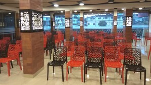 A spacious indoor area with rows of red and black chairs arranged for seating. - Hotel Al Wesal International (Madikeri)