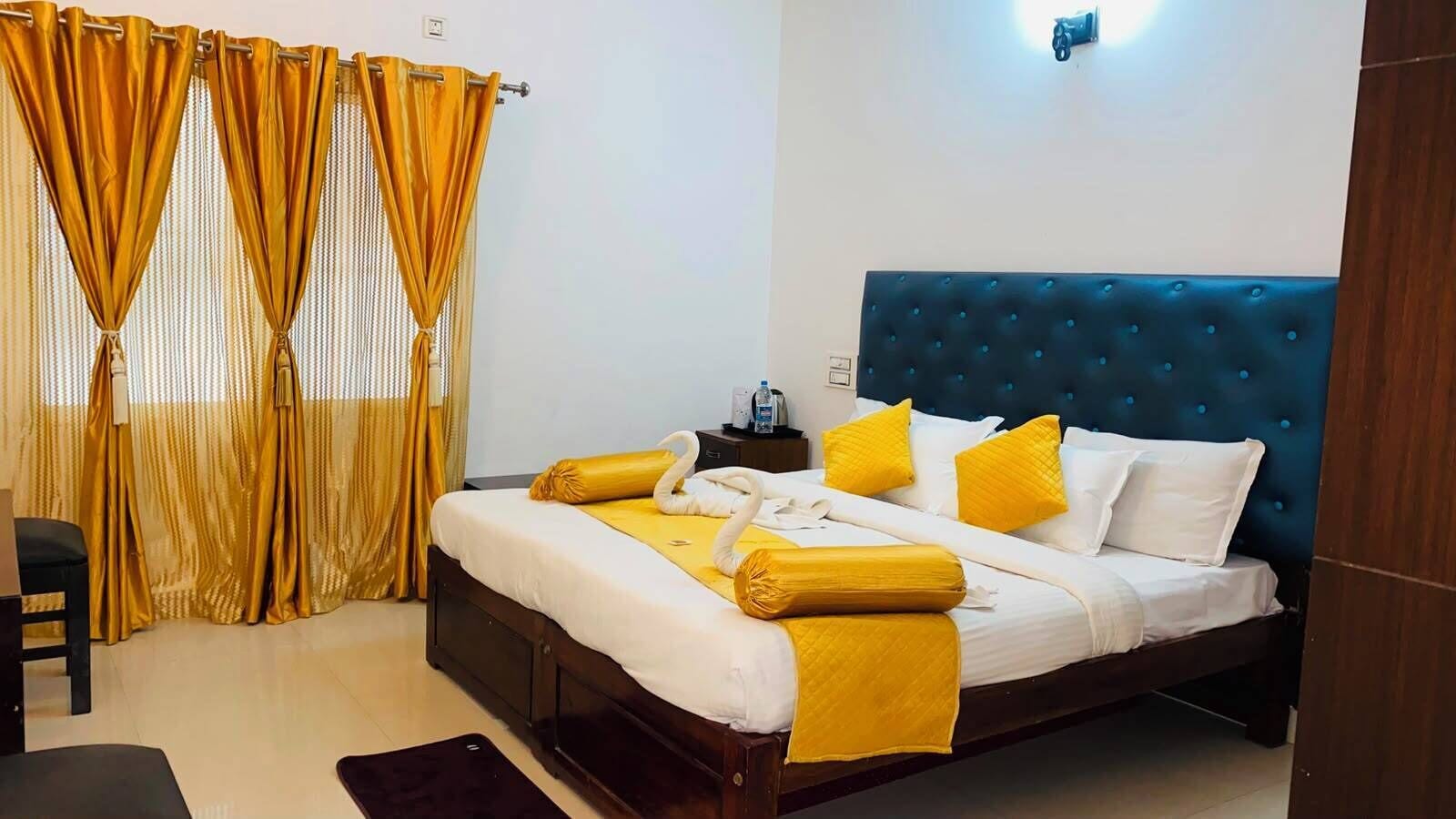 Een hotelkamer met een bed, nachtkastje, stoel en gordijnen.