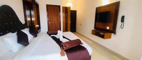 Una habitación de hotel con una cama grande, un televisor montado en la pared y un teléfono.