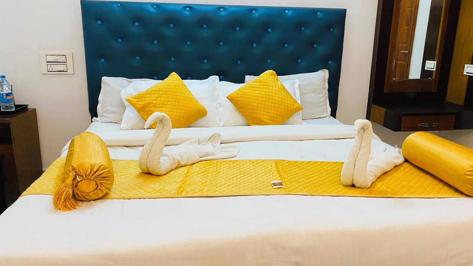 Una cama bien hecha con un cabecero azul, almohadas blancas y amarillas, y una colcha amarilla.