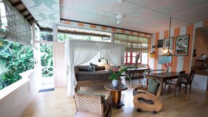 A room with a wooden floor, a bed with a canopy, a dining table, and chairs. - Sayan Ridge Villa (Ubud)