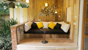 A cozy seating area with a wooden wall, a black and white sofa, and a small round table. - Sayan Ridge Villa (Ubud)