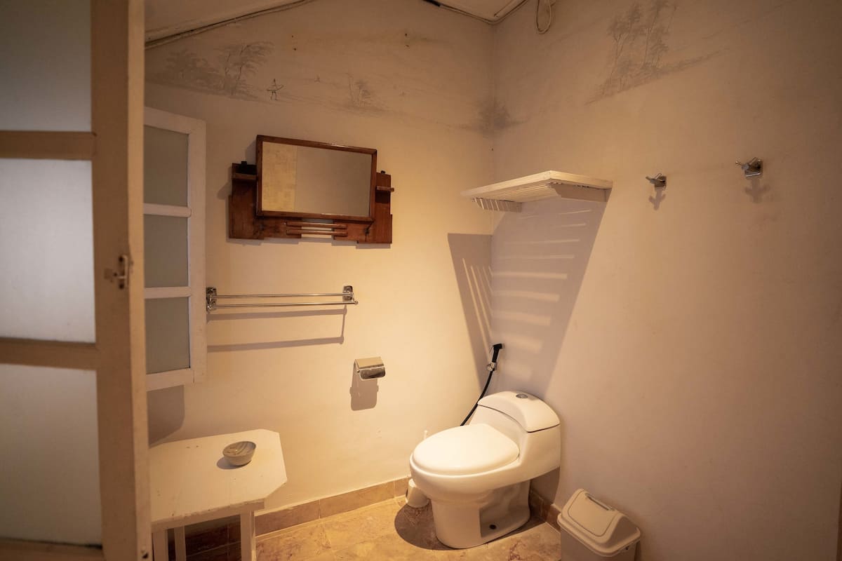 A small, compact bathroom with a toilet, sink, and mirror.