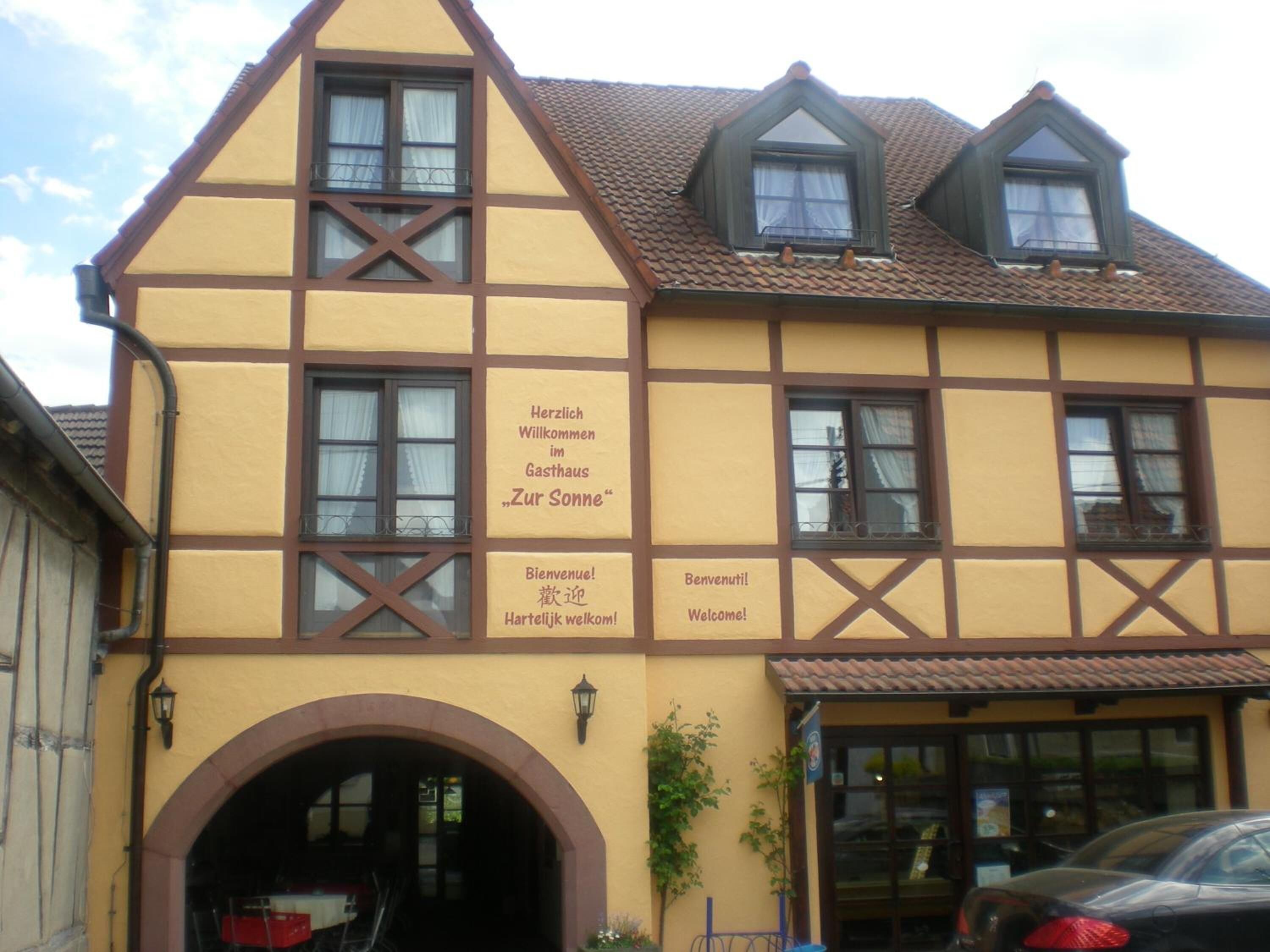 A traditional half-timbered building with a sign welcoming guests to "Zur Sonne" restaurant.